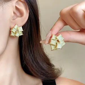 Detail view of minimalist geometric square layered earrings worn by a female model