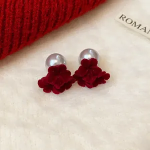 Elegant red flocked flower stud earrings with grey pearls on white plush background
