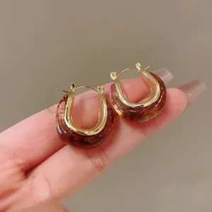 Detailed view of retro U-shaped hoop earrings featuring amber resin and gold metallic finish