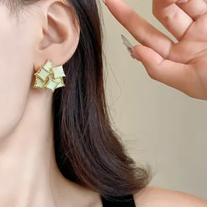 Close-up detail of geometric double-layer square stud earrings with light green enamel finish