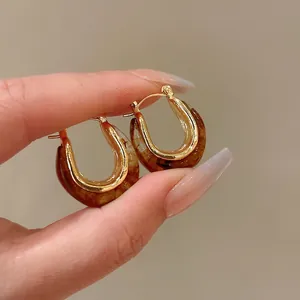 Detailed macro view of vintage U-shaped amber resin earrings with elegant golden accents