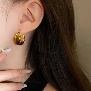 Detail of vintage U-shaped geometric gold earrings with amber marble pattern finish