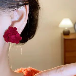 Close-up detail of elegant red flocked flower ear studs with silver needle worn on ear
