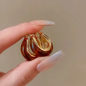 Close-up detail of retro U-shaped hoop earrings with brown resin and gold-tone finish