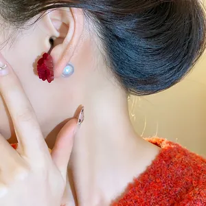 Detail of red flocked flower earring with pearl backing worn on model's ear
