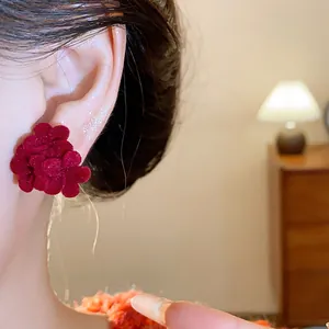 Detailed close-up showing the texture of a red flocked flower earring worn on an ear