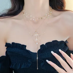 Close-up of a layered gold necklace featuring rhinestone cross and star pendants on a model