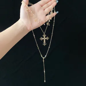 Close-up of gold multi-layered necklace featuring rhinestone cross and star charms