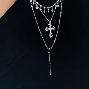 Detailed view of silver layered necklace with rhinestone cross and star charms on black