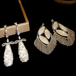 Detailed view of elegant zircon and mother of pearl tassel drop earrings on black background