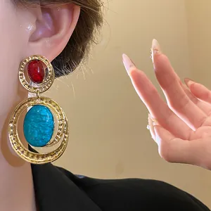 Dettaglio ravvicinato di orecchini vintage in resina ovale dorata indossati da una modella