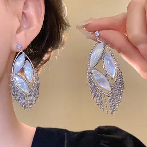 Detailed macro view of silver earrings with mother-of-pearl and dangling tassels