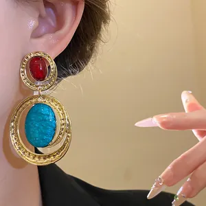 Primo piano di orecchini vintage ovali in resina con pietre blu e rosso oro
