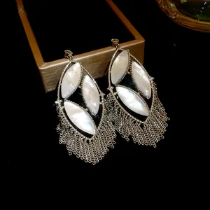 Detailed view of large tassel earrings featuring marquise-shaped white nacre inserts.
