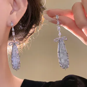 Elegant close-up of silver zircon mother-of-pearl oval tassel earrings with bow