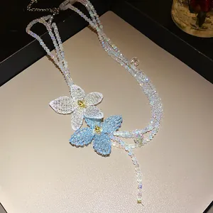 Primer plano de un collar de cuentas iridiscentes con detalles de flores tejidas azul y blanco
