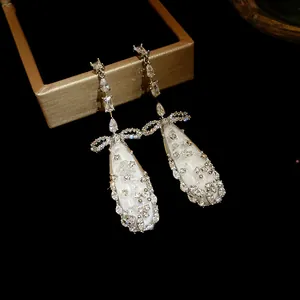 Detailed view of elegant zircon and mother-of-pearl drop earrings on a jewelry box