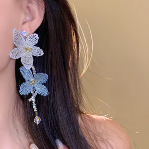 Primer plano de pendientes largos con flores de malla y cuentas irisadas