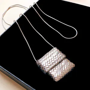 Vista macro dettagliata di un ciondolo a borsa intrecciata argento su collana a catena lunga