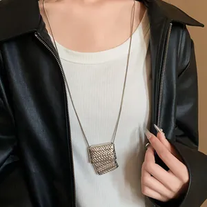 Dettaglio della collana con ciondolo a borsa intrecciata su lunga catena a serpente.