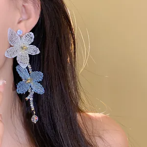Primer plano de un elegante pendiente floral con pétalos de malla y cuentas.