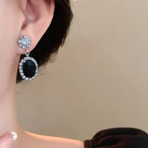 Close-up detail of elegant oval black stone earrings with zircon halo for weddings