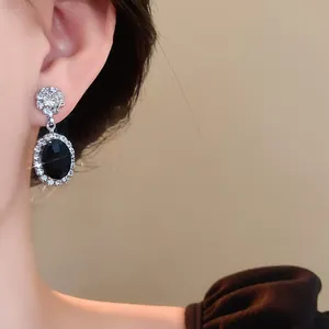 Close-up detail of a vintage style sparkling zircon drop earring featuring an oval black stone