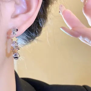 Dettaglio ravvicinato di orecchini in argento a forma di C con zirconi e motivi a stella