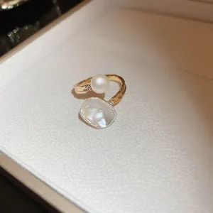 Détail d'une bague en perles d'eau douce plaquée or au design de pétales dans un écrin