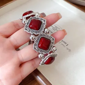 Detailed view of a vintage style elastic bracelet with red stones and ornate silver frames