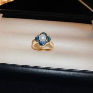 Gros plan détaillé d'une bague fleur plaquée or avec incrustations de nacre bleue et perle