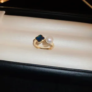 Détail d'une bague plaquée or avec motif trèfle à quatre feuilles et une perle blanche.