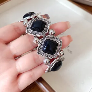 Close-up of vintage court style bracelet with black square acrylic and ornate silver frames