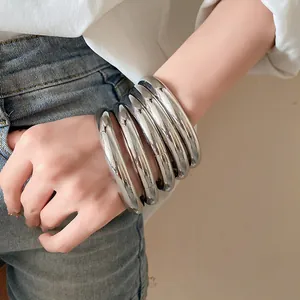 Détail en gros plan d'un ensemble de bracelets ronds argentés sur un poignet féminin