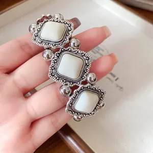 Detail of a vintage court style elastic bracelet with white acrylic stones and silver frames.