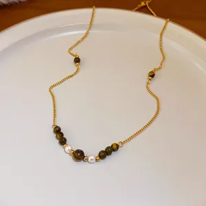Detail einer goldenen Vintage-Halskette mit braunen Tigerauge-Perlen und eleganten weißen Perlen.