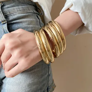 Gros plan détaillé d'un ensemble de bracelets ronds dorés brillants sur un poignet de femme