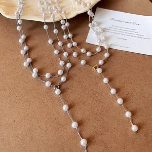 Close-up of two elegant long necklaces with white faux pearls and metallic chains