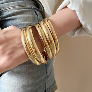 Détail montrant un empilement de joncs en métal doré brillant sur le poignet d'une femme
