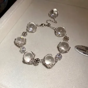 Elegantes Glasperlenarmband mit silbernen Schneeflockenanhängern auf einem Tablett.