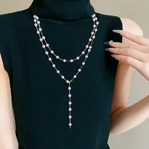 Close-up of elegant double-layered artificial pearl necklace worn over a black sweater.