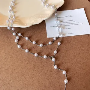 Close-up of French style long artificial pearl necklace on a vintage background.
