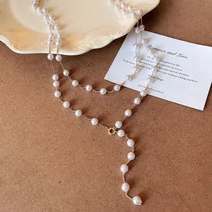 Detail view of a French style long faux pearl Y-necklace with gold chain elements.