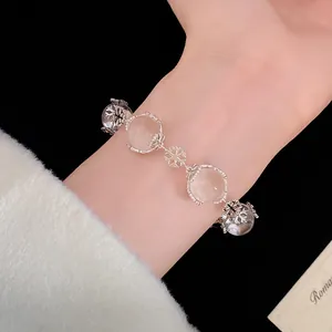Nahaufnahme eines eleganten Armbands mit Schneeflocken-Anhängern und Glaskugeln