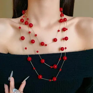 Detail view of vintage multi-layer long necklace with glossy red faux pearls on gold chain.