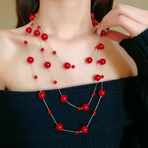 Detailed view of layered retro red pearl necklace draped on an elegant black top