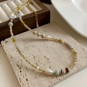 Primo piano di una collana vintage di perle e gemme su una lastra di pietra