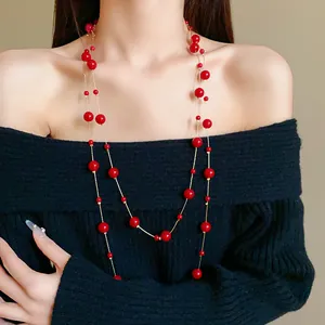 Detail view showing a long vintage red faux pearl sweater chain worn by a model