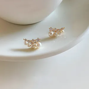 Close-up of elegant 18k gold plated stud earrings with zircons and white pearls.