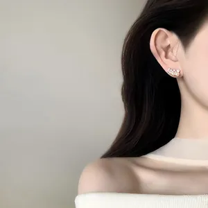 Close-up detail of elegant zircon and pearl cluster stud earrings on a model's ear